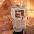 Load image into Gallery viewer, Child holding a newspaper titled 'Avalon Tales' in a cozy bedroom setting.
