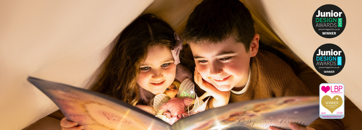 Two children smiling while reading My Forever Tooth Fairy Storybook under warm, soft light inside a cozy tent-like setting. Award badges for 'Junior Design Awards' and a 'LBP Winner' logo are displayed on the right side of the image.